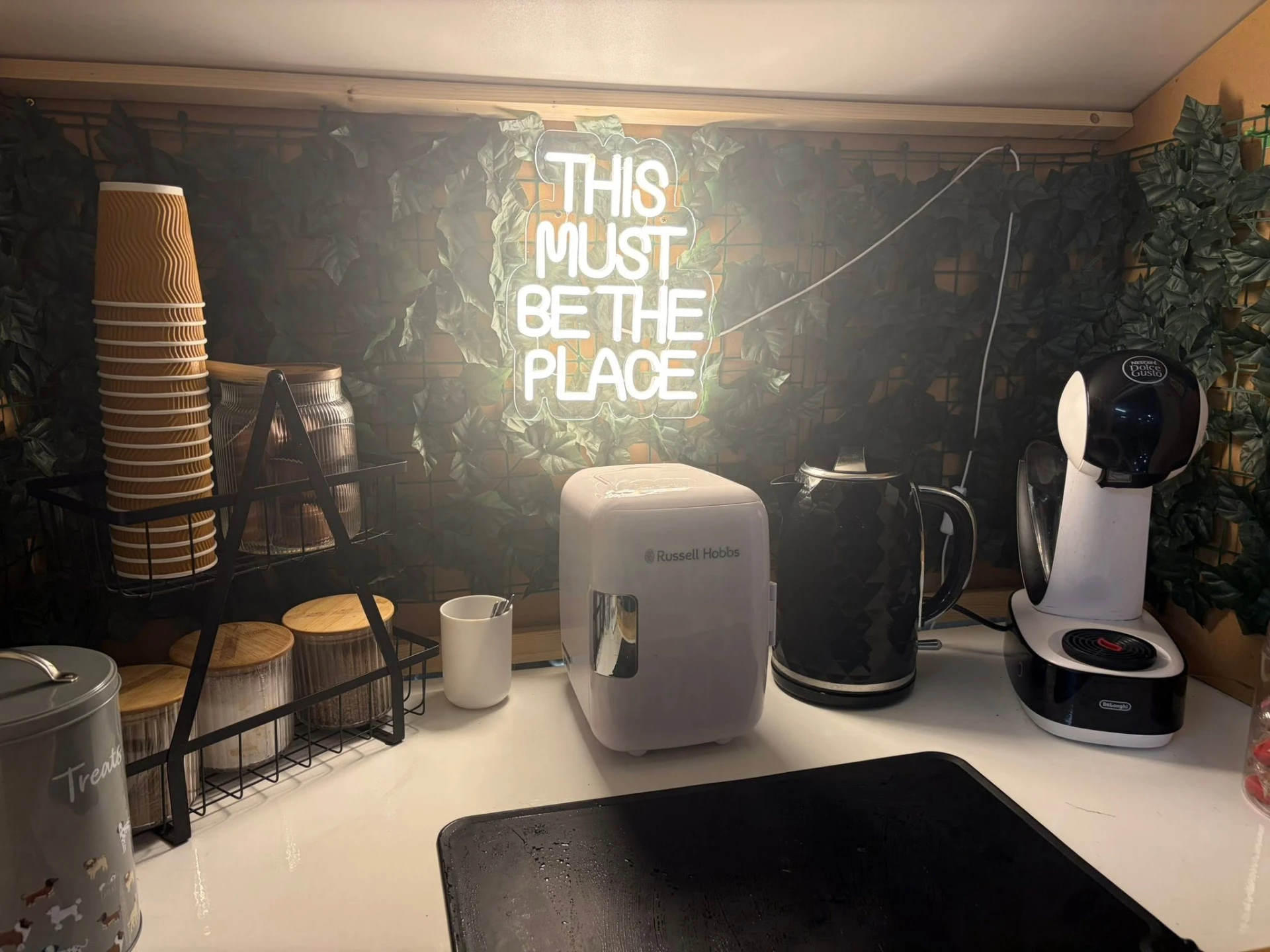 Free hot drinks station with kettle, coffee machine and neon 'This must be the place' sign at Sit.Stay.Play